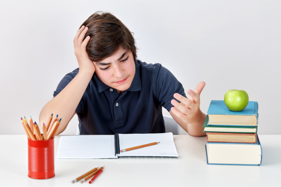Image shows a student sitting at a desk, confused